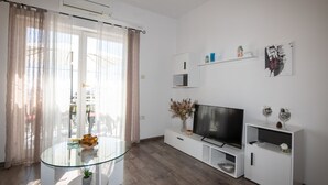 A modern living room with a glass table, white entertainment unit, and a flat-screen TV. - Apartments Mirjana IKA (Ika)