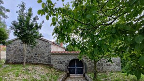 A stone pathway leading to a building with a tiled roof and a black door.