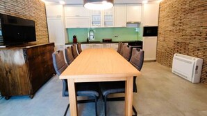 A modern kitchen with white cabinets, a wooden dining table, and black chairs.