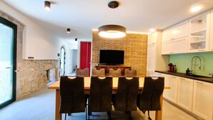 A modern kitchen with a dining area, a stone wall, and a TV mounted above the counter.