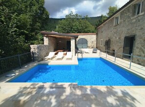 A swimming pool with lounge chairs, a stone building, and a stone wall. - Villa Galant Brgudac - Private Oasis With Pool (Lanisce)