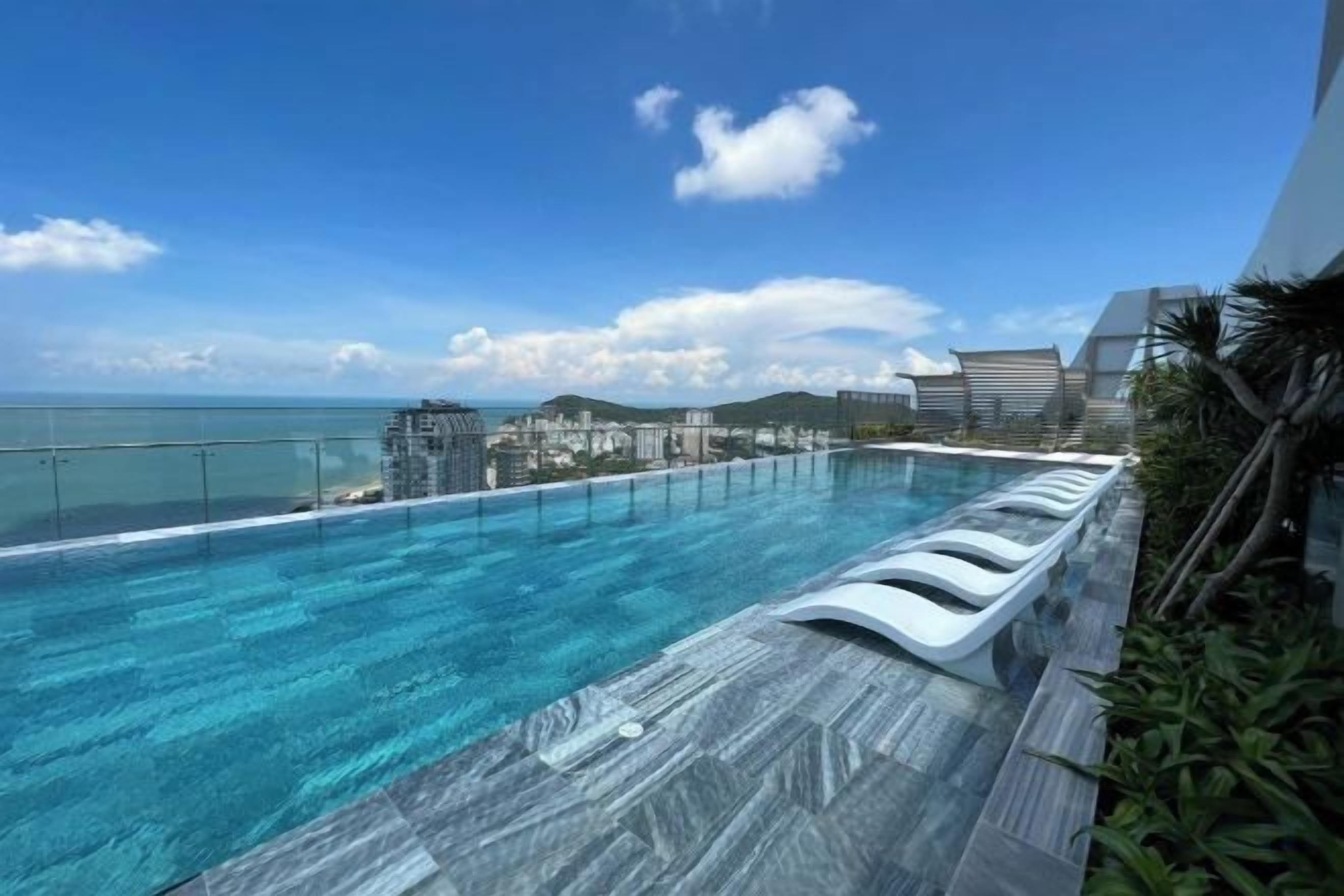 A rooftop infinity pool with a clear view of the ocean and cityscape.