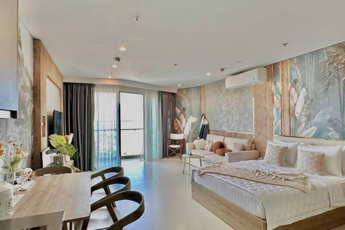 Ein modernes Hotelzimmer mit einem großen Bett, einem Essbereich mit Tisch und Stühlen sowie einer Sitzecke mit Sofa und Fernseher.
