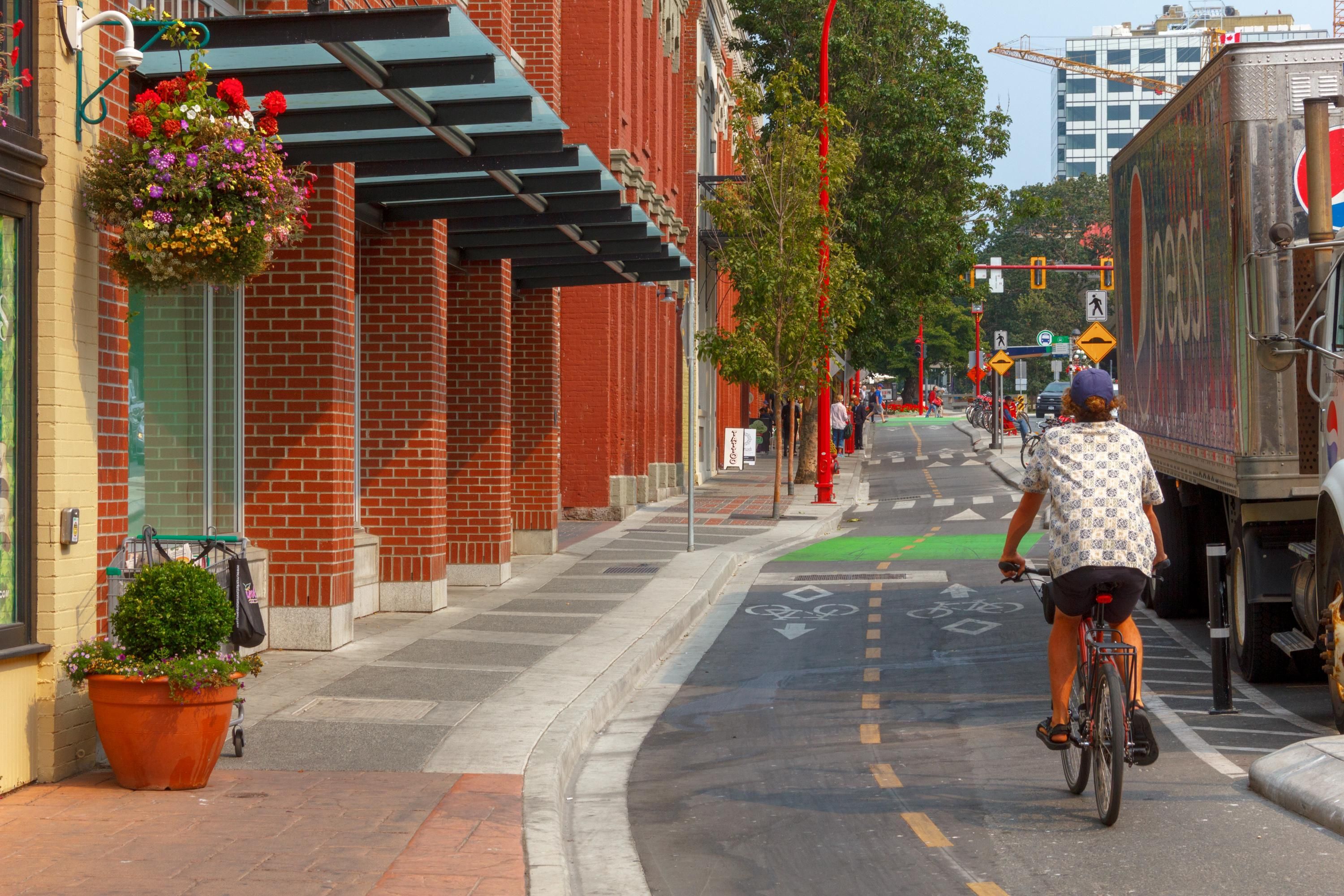 A street with a cyclist, a truck, and a building with a brick facade.