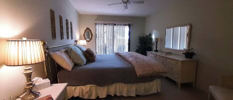 Un dormitorio con cama, mesita de noche, lámpara, cómoda y ventilador de techo.