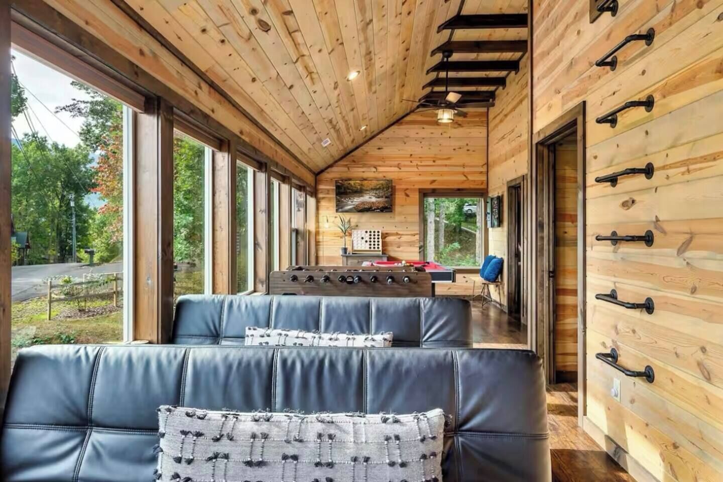 Ein Blockhaus-Interieur mit einem langen Esstisch, Ledersitzgelegenheiten und Holzwänden.