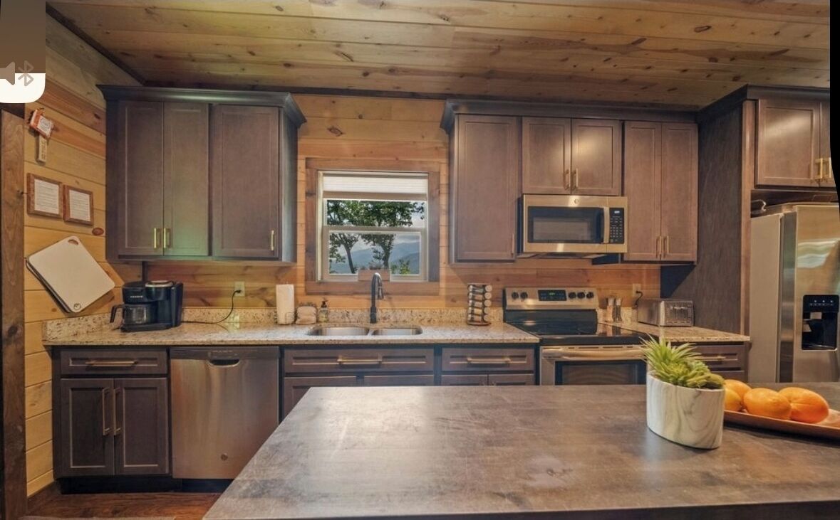 A modern kitchen with wooden cabinets, stainless steel appliances, and a large island.