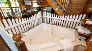 Una baita di legno con bagno rivestito di piastrelle bianche, dotato di una grande vasca e una panca in legno.