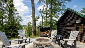 Una baita di tronchi con un focolare in pietra circondato da poltrone Adirondack.