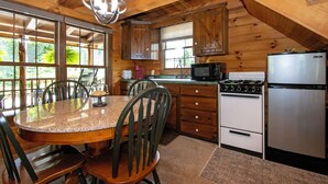 Una cucina in legno con tavolo e sedie, un fornello, un forno a microonde e un frigorifero.