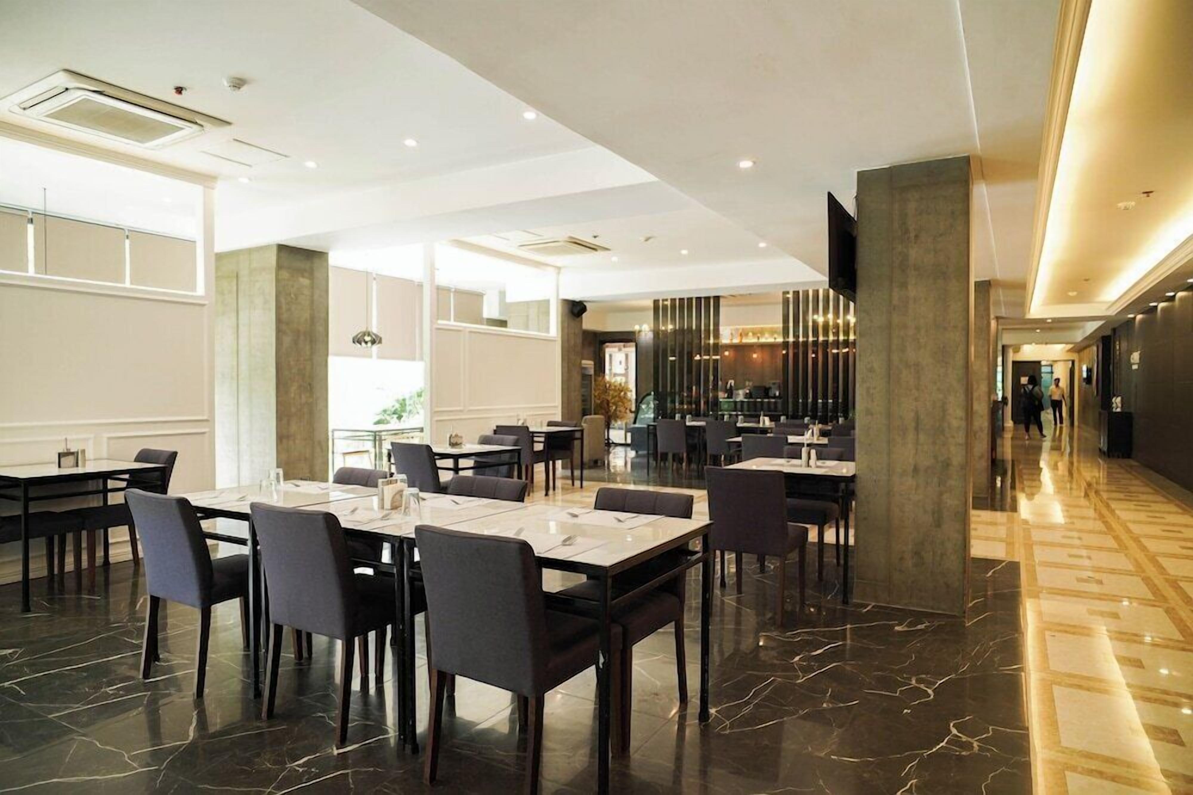A modern dining area with marble flooring, multiple tables, and chairs.