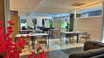 Un'accogliente hall d'albergo con diversi tavoli da pranzo, sedie e un divano.