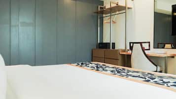 Quarto de hotel com cama, escrivaninha, cadeira, cômoda, espelho e ar condicionado.
