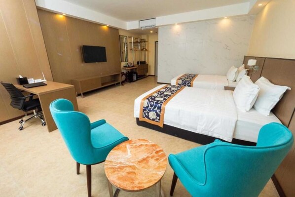 Una habitación de hotel con cama, dos sillas, escritorio, televisor y espejo.