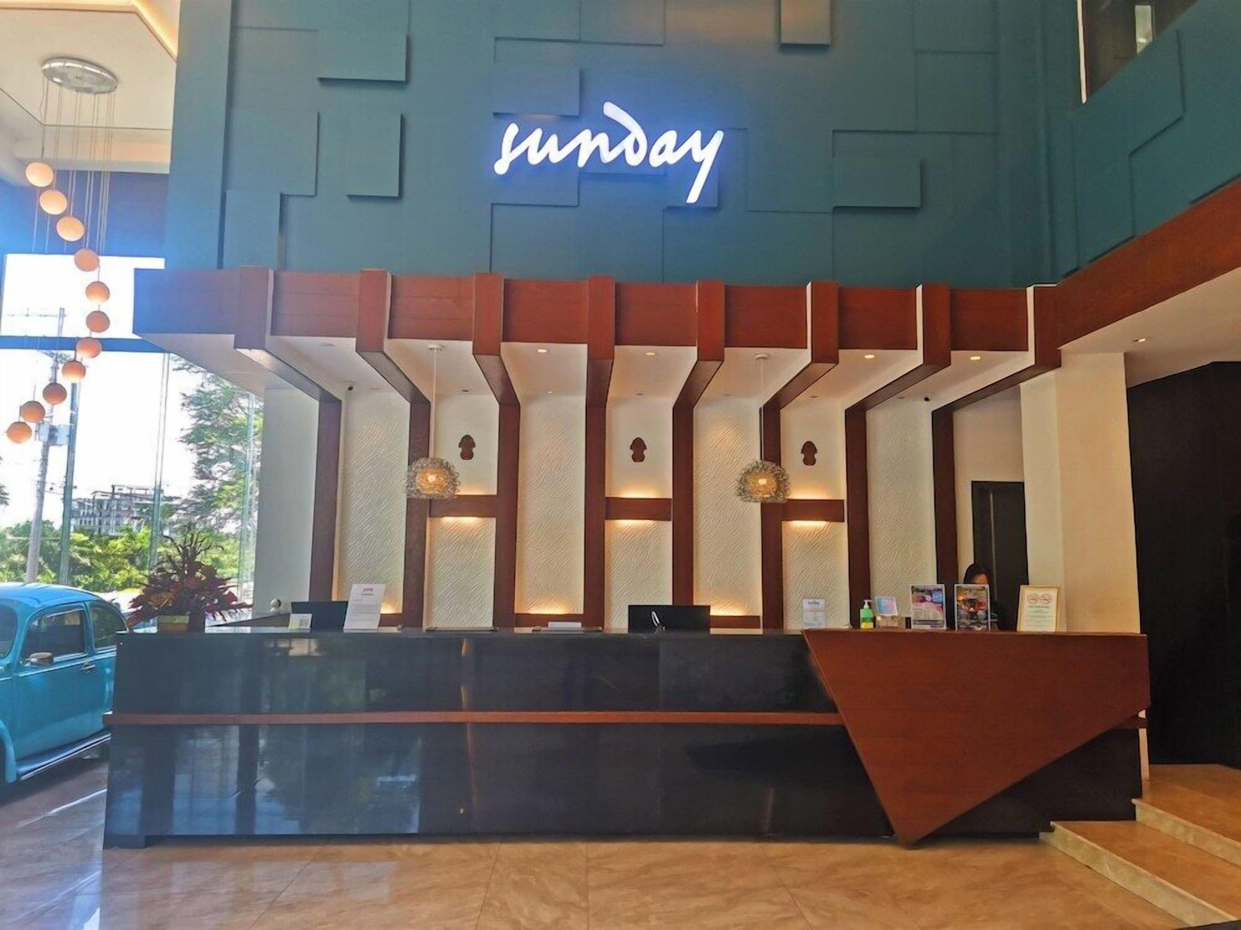 A reception desk with a neon sign, a modern design, and a car parked outside.