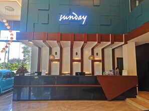 A reception desk with a neon sign, a modern design, and a car parked outside. - Sunday Hevea Hotel and Resort (Angeles)