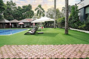 Un patio trasero con piscina, sillas de descanso y un área de estar techada.