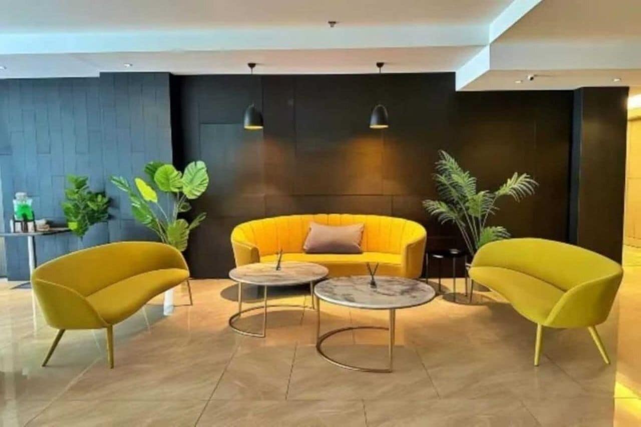 Een moderne lobby met een geel bankje, twee gele fauteuils en een bijzettafeltje.