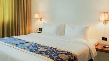 Een hotelkamer met een groot bed, twee bedlampjes, een nachtkastje en een gordijn.