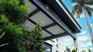 Un hotel moderno con un cartello ben visibile, immerso nel verde e sotto un cielo limpido.
