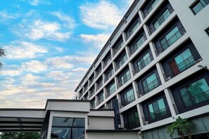 Un edificio de varios pisos con un diseño arquitectónico moderno, con balcones y ventanas amplias.