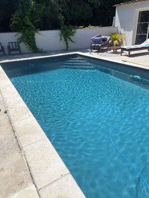 Ein rechteckiger Swimmingpool mit klarem, blauem Wasser, umgeben von einer gefliesten Liegefläche.