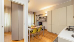 Una cocina moderna con comedor, suelo de madera y televisión empotrada.