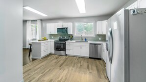 Una cocina moderna con armarios blancos, un refrigerador de acero inoxidable y un microondas empotrado.