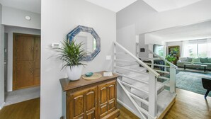 Una sala de estar moderna con una escalera, armarios de madera y un espejo grande.