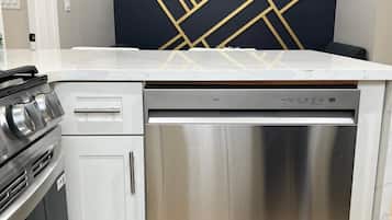A modern kitchen with a stainless steel dishwasher, a built-in oven, and a gas stove.