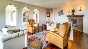 Ein Wohnzimmer mit Ledersesseln, einem weißen Sofa, einem gemusterten Teppich und einem Kamin.