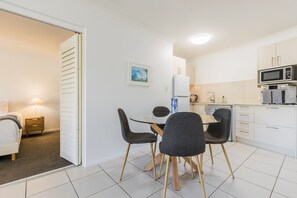 A compact living space with a dining area, kitchenette, and a bedroom. - Narli Shores • Coastal Studio for 4 • Private Spa (Agnes Water)