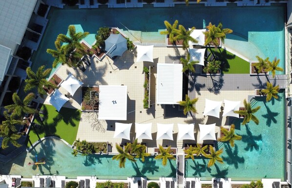 An aerial view of a resort with a swimming pool, palm trees, and sun loungers. - Narli Shores • Coastal Studio for 4 • Private Spa (Agnes Water)