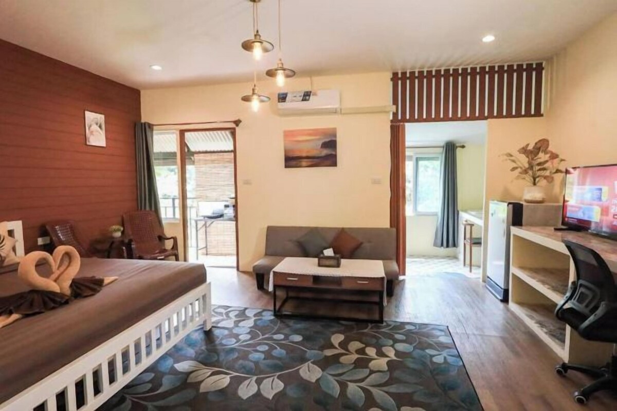 A hotel room with a bed, sofa, desk, and a view of the outside.