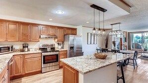 A modern kitchen with wooden cabinets, stainless steel appliances, granite countertops, and a large island.