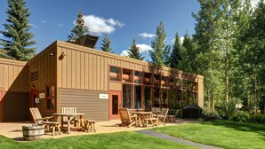 A wooden building with a pool area, outdoor seating, and a barbecue grill.