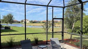 A covered patio with outdoor seating and a view of a lake and houses.