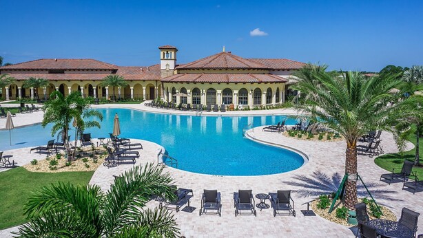 A resort with a large swimming pool, lounge chairs, and palm trees.