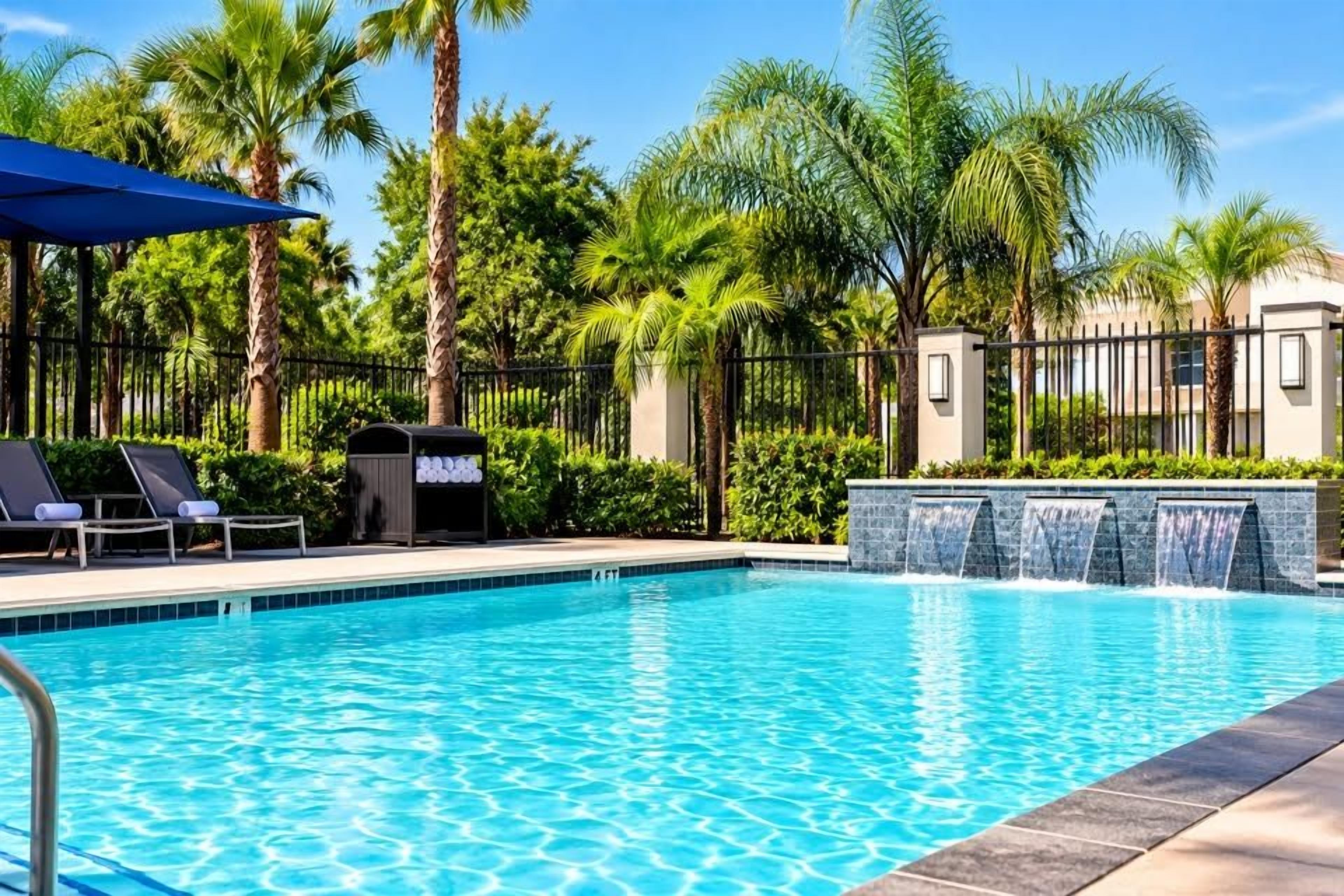 A swimming pool with lounge chairs and a waterfall feature.