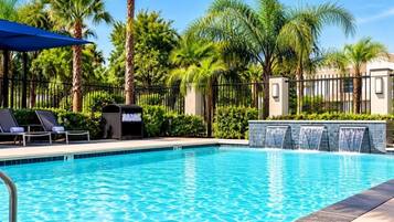 A swimming pool with lounge chairs and a waterfall feature.