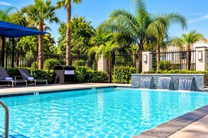 Una piscina con sillones de descanso y una cascada.