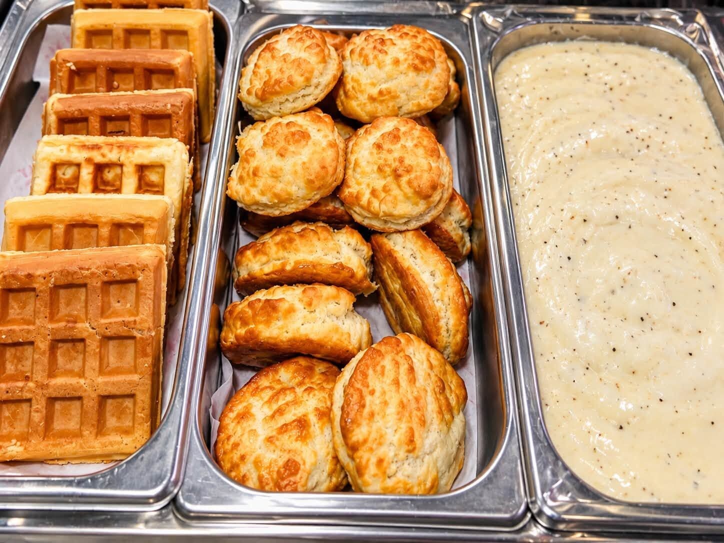 Un bufé con gofres, pasteles y salsa cremosa.