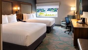 A hotel room with two beds, a desk, a chair, and a TV.
