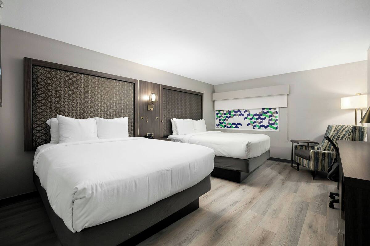 Habitación de hotel con dos camas, un escritorio y una silla.