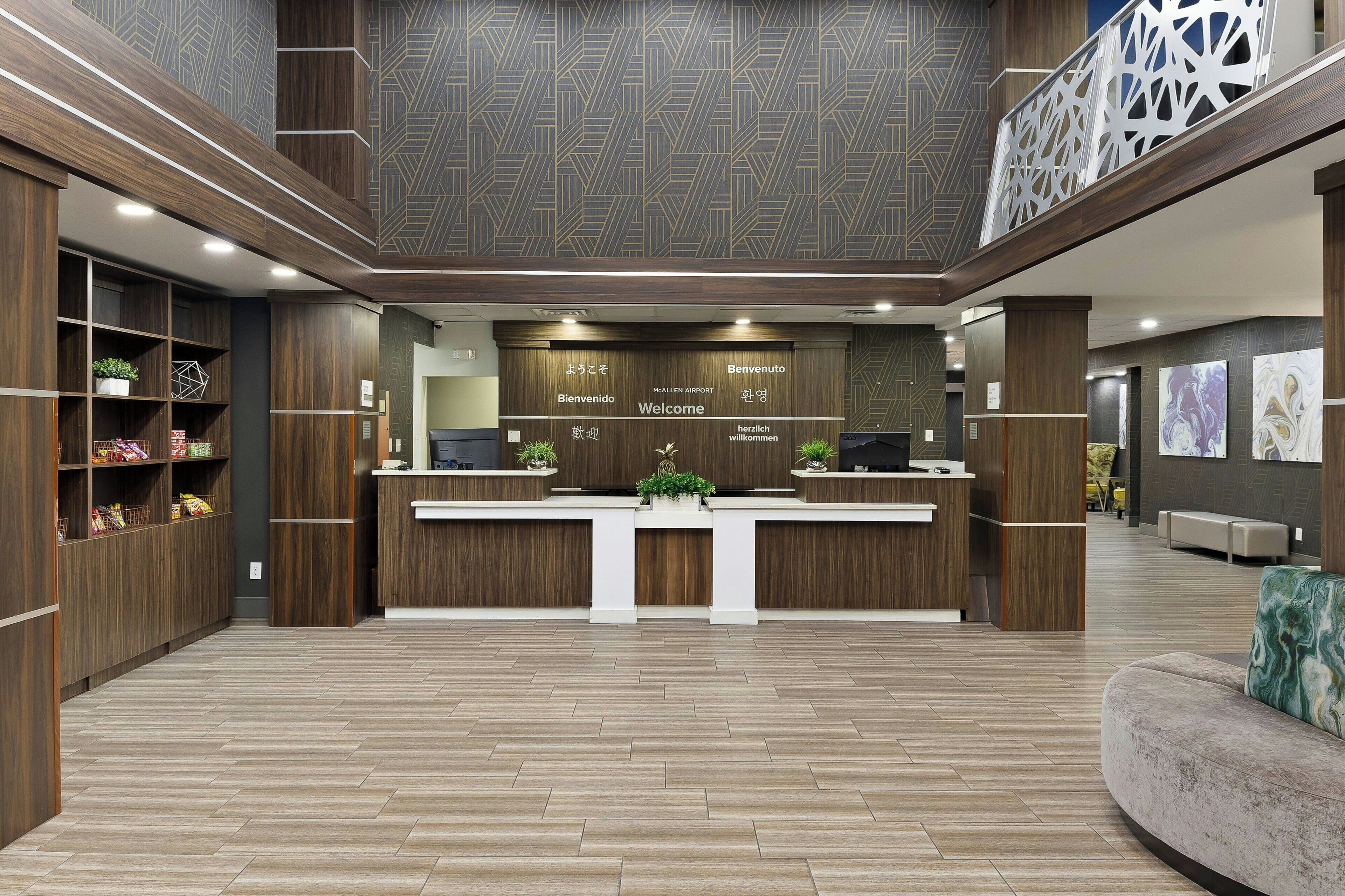 A modern reception area with a wooden reception desk, a seating area, and a patterned ceiling.
