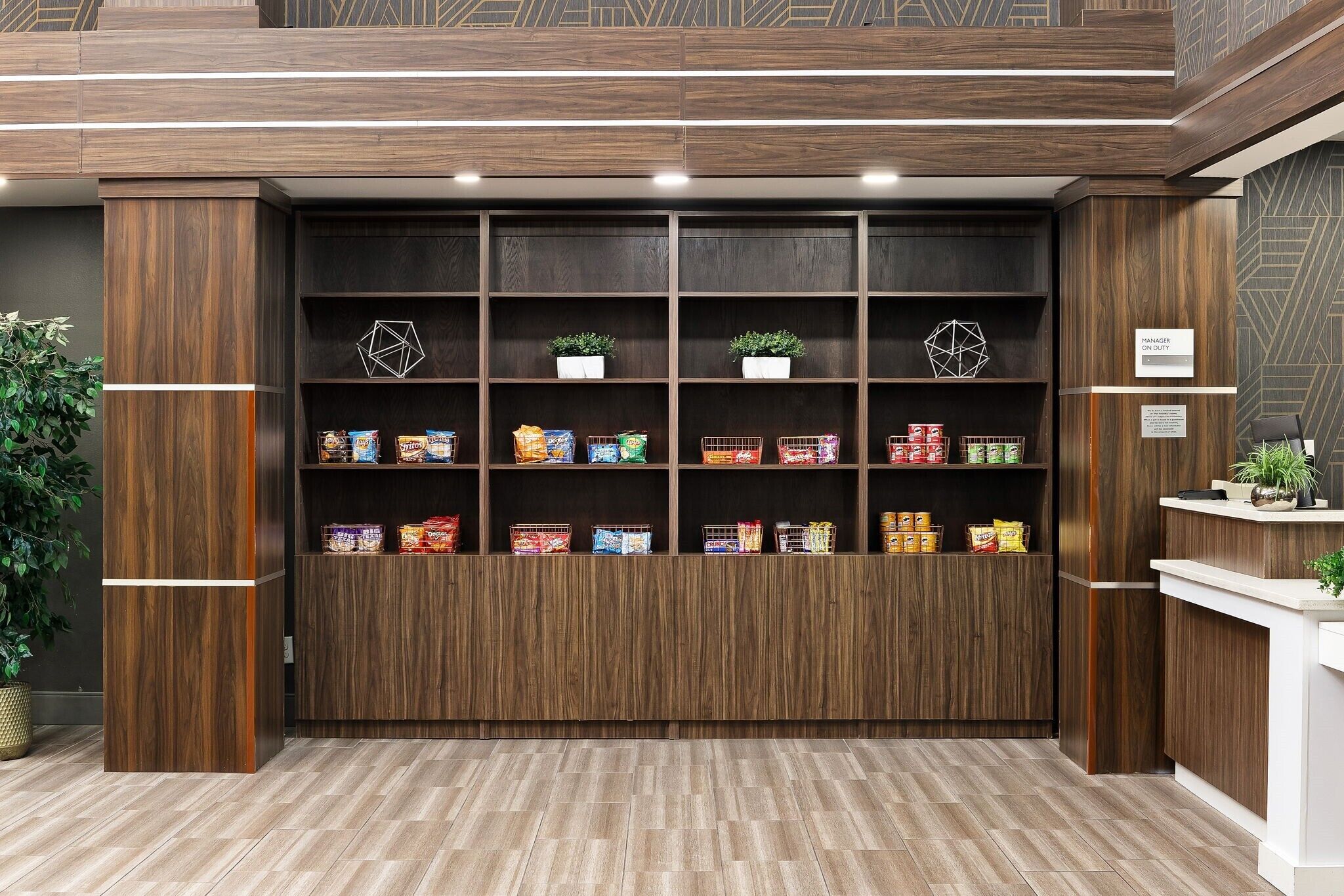 A reception area with wooden paneling, a reception desk, and shelves stocked with snacks and beverages.