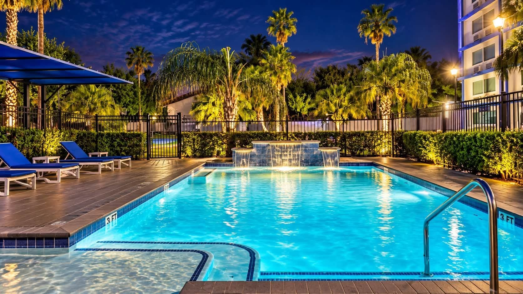 A swimming pool with a 3 FT depth marker, surrounded by palm trees and lounge chairs.