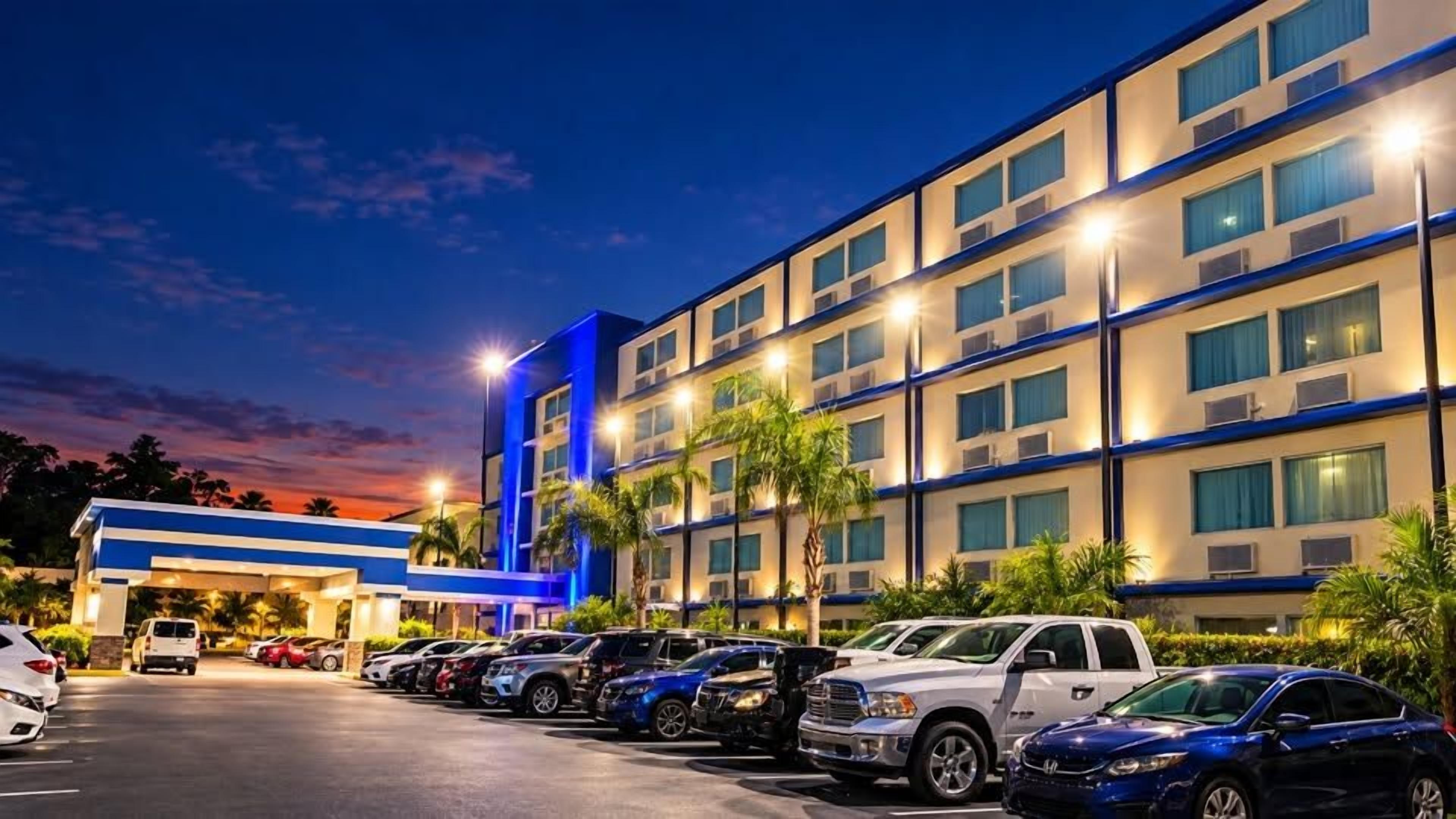 A multi-story hotel with a parking lot in front.