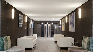 Uma área de recepção com design moderno, com balcão de atendimento, duas poltronas de espera e um painel de parede com padrão.