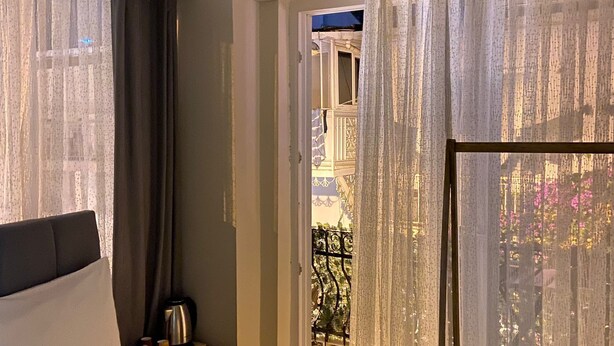 Une chambre d’hôtel avec un lit, une petite table et une bouilloire, et donnant sur le balcon extérieur.